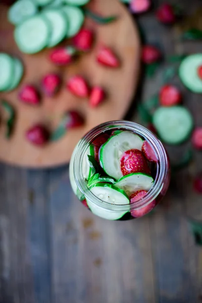 Strawberry mint cucumber infused water decorated in rustic style on dark wood table background — Stock Photo, Image