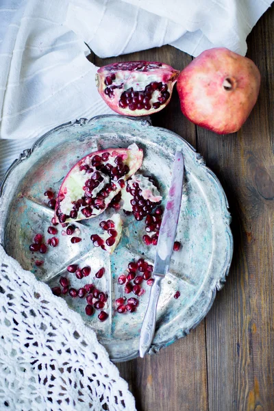 Organic pomegranate open cut in half and full one on a wooden dark table background decorated in rustic style — Stock Photo, Image