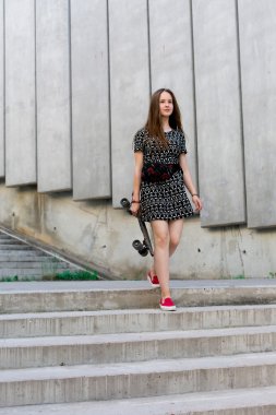 uzun muhteşem saçlı güzel genç ve güzel beyaz sarışın genç hipster patenci kız gülümseyerek ve şaşırtıcı yaz gündüz ile onun sevimli küçük paten buz pateni süre dışarıda eğleniyor poz