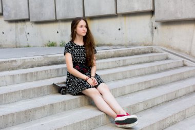 uzun muhteşem saçlı güzel genç ve güzel beyaz sarışın genç hipster patenci kız gülümseyerek ve şaşırtıcı yaz gündüz ile onun sevimli küçük paten buz pateni süre dışarıda eğleniyor poz