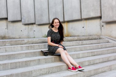 uzun muhteşem saçlı güzel genç ve güzel beyaz sarışın genç hipster patenci kız gülümseyerek ve şaşırtıcı yaz gündüz ile onun sevimli küçük paten buz pateni süre dışarıda eğleniyor poz