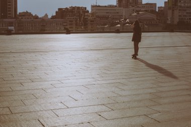 uzun muhteşem saçlı güzel genç ve güzel beyaz sarışın genç hipster patenci kız günbatımı sırasında cityscape bir arka plan üzerinde paten