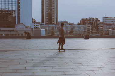 gülen ve having fun dışında kaykayıyla şaşırtıcı yaz gün boyunca şehirde buz pateni yaparken poz bir şapka giyen havalı genç ve yakışıklı beyaz esmer hipster patenci adam