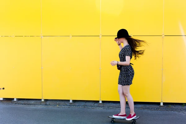 Fresco joven y hermosa caucásica rubia adolescente hipster skater chica con el pelo largo y hermoso está posando sonriente y divertirse al aire libre mientras patina con su pequeño patín lindo durante el increíble día de verano — Foto de Stock