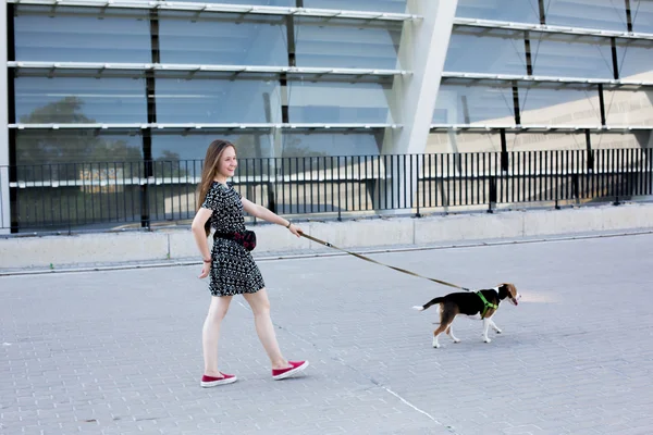 Portrait of cool young and beautiful caucasian blonde teenager hipster girl with long gorgeous hair is posing smiling and having fun with her beagle puppy dog — Stock Photo, Image