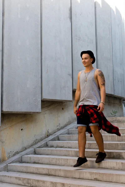 Coole junge und gut aussehende kaukasische brünette Hipster-Skater-Typ mit Hut posiert lächelnd und Spaß draußen während erstaunliche Sommertag in der Stadt mit — Stockfoto