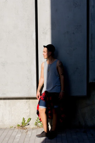 Fresco joven y guapo caucásico morena hipster skater chico con un sombrero posando sonriente y divertirse fuera durante increíble día de verano en la ciudad con —  Fotos de Stock