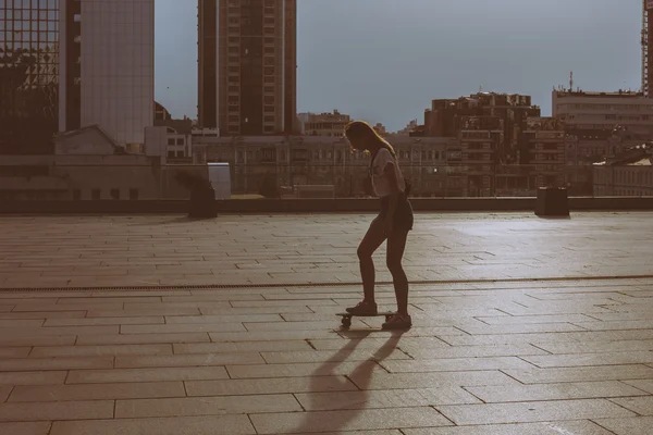 Legal jovem e bonito caucasiano loira hipster skatista menina vestindo shorts jeans posando sorrindo e se divertindo fora enquanto patina com ela bonito pouco skate durante incrível verão dia — Fotografia de Stock