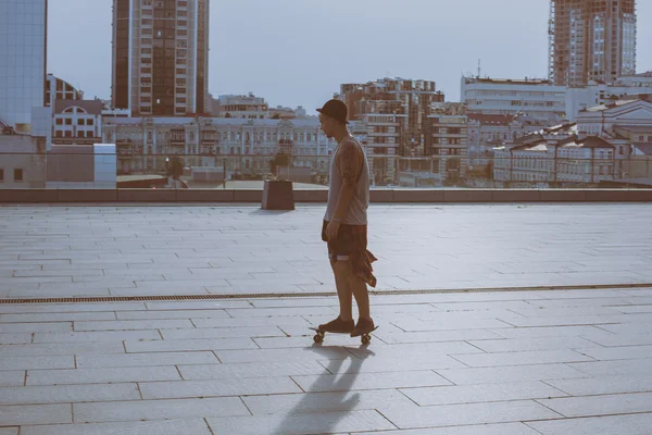 Fresco joven y guapo caucásico morena hipster skater chico usando un sombrero posando sonriendo y divertirse al aire libre mientras patina con su monopatín durante increíble día de verano en la ciudad —  Fotos de Stock