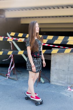 uzun muhteşem saçlı güzel genç ve güzel beyaz sarışın genç hipster patenci kız gülümseyerek ve şaşırtıcı yaz gündüz ile onun sevimli küçük paten buz pateni süre dışarıda eğleniyor poz