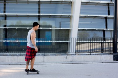 gülen ve having fun dışında kaykayıyla şaşırtıcı yaz gün boyunca şehirde buz pateni yaparken poz bir şapka giyen havalı genç ve yakışıklı beyaz esmer hipster patenci adam