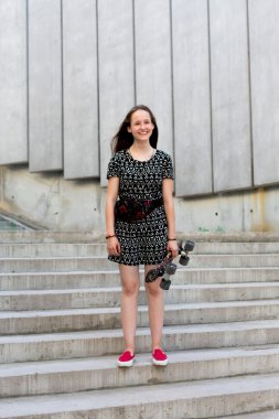 uzun muhteşem saçlı güzel genç ve güzel beyaz sarışın genç hipster patenci kız gülümseyerek ve şaşırtıcı yaz gündüz ile onun sevimli küçük paten buz pateni süre dışarıda eğleniyor poz