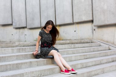 uzun muhteşem saçlı güzel genç ve güzel beyaz sarışın genç hipster patenci kız gülümseyerek ve şaşırtıcı yaz gündüz ile onun sevimli küçük paten buz pateni süre dışarıda eğleniyor poz