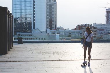 gülümseyen ve onun sevimli küçük kaykay ile şaşırtıcı yaz gün boyunca paten yaparken eğlenmek dışında poz kot şort giyen havalı genç ve güzel beyaz sarışın hipster patenci kız