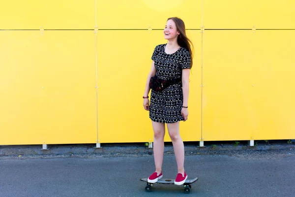 Fresco joven y hermosa caucásica rubia adolescente hipster skater chica con el pelo largo y hermoso está posando sonriente y divertirse al aire libre mientras patina con su pequeño patín lindo durante el increíble día de verano — Foto de Stock