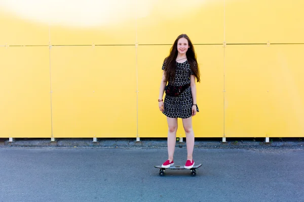 Cool young and beautiful caucasian blonde teenager hipster skater girl with long gorgeous hair is posing smiling and having fun outside while skating with her cute little skate during amazing summer day — Stock Photo, Image