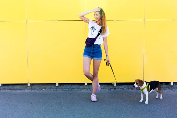 Cool young and beautiful caucasian blonde hipster girl wearing denim shorts posing smiling and having fun outside with her beagle puppy dog during amazing summer day — Stock Photo, Image