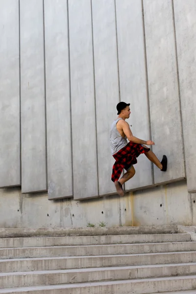 Fresco joven y guapo caucásico morena hipster skater chico con un sombrero posando sonriente y divertirse fuera durante increíble día de verano en la ciudad con —  Fotos de Stock