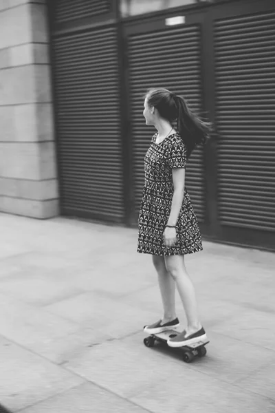 Fresco joven y hermosa caucásica rubia adolescente hipster skater chica con el pelo largo y hermoso está posando sonriente y divertirse al aire libre mientras patina con su pequeño patín lindo durante el increíble día de verano — Foto de Stock