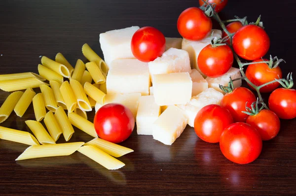 Grana padano italiana, pasta y tomates sobre fondo de madera oscura — Foto de Stock