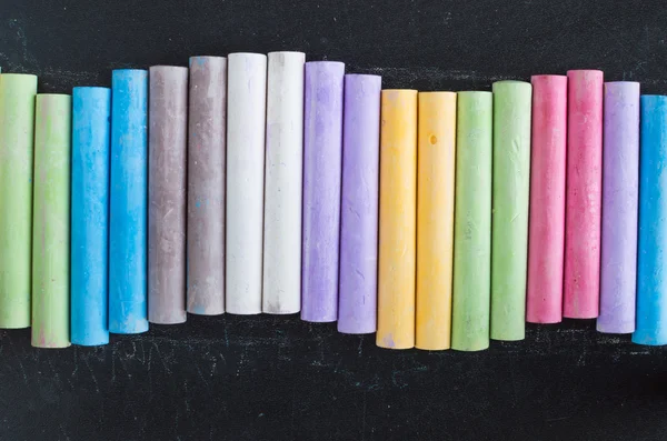 Colorful chalks lined up on blackboard background — Stock Photo, Image