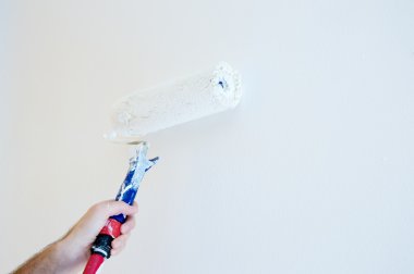 Adult painter whitewash with roll on white wall