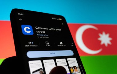 Azerbaycan bayrağının arka planına sahip akıllı telefon ekranında Coursera uygulaması. Bakü, Azerbaycan. 11.26.2025.