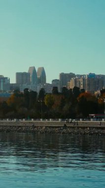 İnsanlar ve gezginler Bakü Bulvarı 'nda yürüyor, konuşuyor ya da eğleniyorlar. Soğuk ruh hali, martılar ve görkemli günbatımı anı. Bakü, Azerbaycan. 13.12.2025.