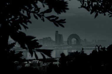 Kasvetli bir gökyüzü altında Bakü 'nün dramatik şehir manzarası cesur mimari, canlı şehir enerjisi ve Azerbaycan başkentinin dinamik ruhunu sergiliyor..