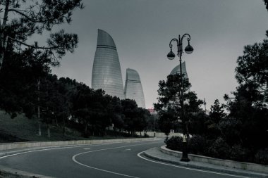 Kasvetli bir gökyüzü altında Bakü 'nün dramatik şehir manzarası cesur mimari, canlı şehir enerjisi ve Azerbaycan başkentinin dinamik ruhunu sergiliyor..