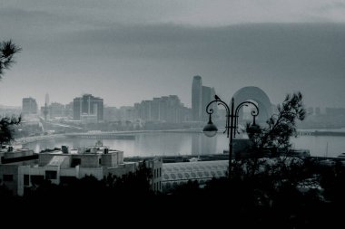 Kasvetli bir gökyüzü altında Bakü 'nün dramatik şehir manzarası cesur mimari, canlı şehir enerjisi ve Azerbaycan başkentinin dinamik ruhunu sergiliyor..