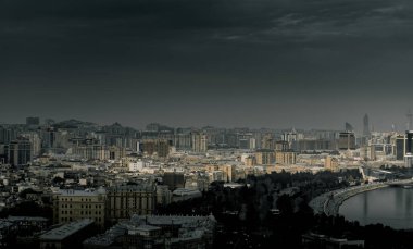 Kasvetli bir gökyüzü altında Bakü 'nün dramatik şehir manzarası cesur mimari, canlı şehir enerjisi ve Azerbaycan başkentinin dinamik ruhunu sergiliyor..
