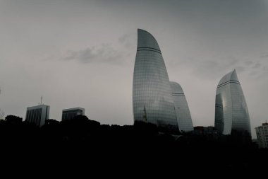 Kasvetli bir gökyüzü altında Bakü 'nün dramatik şehir manzarası cesur mimari, canlı şehir enerjisi ve Azerbaycan başkentinin dinamik ruhunu sergiliyor..