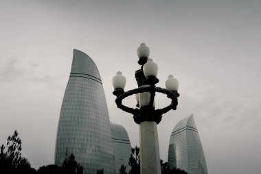 Kasvetli bir gökyüzü altında Bakü 'nün dramatik şehir manzarası cesur mimari, canlı şehir enerjisi ve Azerbaycan başkentinin dinamik ruhunu sergiliyor..