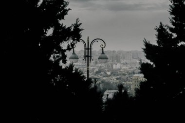 Kasvetli bir gökyüzü altında Bakü 'nün dramatik şehir manzarası cesur mimari, canlı şehir enerjisi ve Azerbaycan başkentinin dinamik ruhunu sergiliyor..
