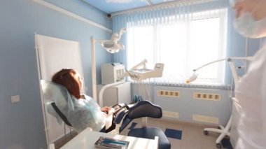 Kadın dişçi hastalarının dişlerinde çalışıyor.