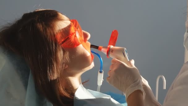 Dentista que trabalha com lâmpada de polimerização dentária na cavidade oral . — Vídeo de Stock