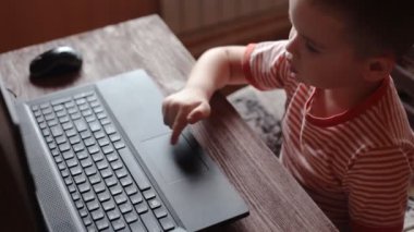 Küçük çocuk evde bir dizüstü bilgisayar kullanarak