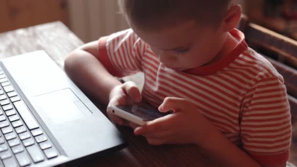 Niño utiliza el teléfono inteligente en casa — Vídeo de stock