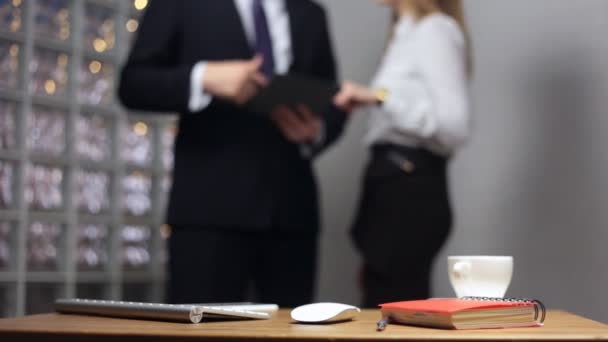 Documents sur table de bureau et homme et femme parlant en arrière-plan — Video