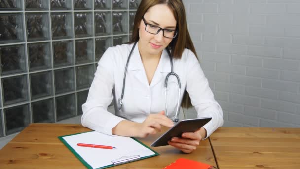 Kobieta lekarz za pomocą tabletu pc w biurze — Wideo stockowe