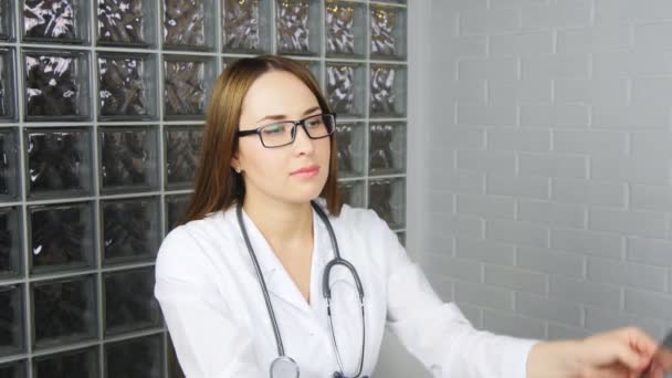 Médico joven y agradable observando una radiografía de paciente en el hospital — Vídeo de stock