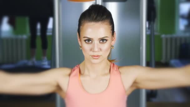 Frau beim Fitnesstraining auf einem Butterfly-Gerät mit Gewichten in einem Fitnessstudio — Stockvideo