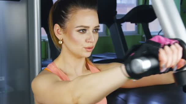 Kvinnan gör konditionsträning på en fjäril maskin med vikter i ett gym — Stockvideo