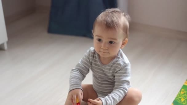Niedliches kleines Baby spielt mit buntem Spielzeug zu Hause — Stockvideo