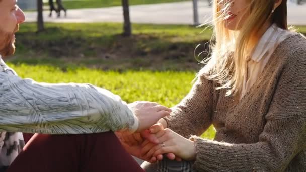 Молода пара сидить у парку — стокове відео