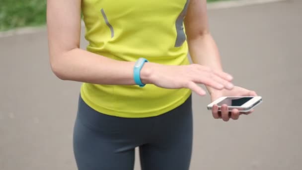 Жіночі руки зі спортивним браслетом і смартфоном — стокове відео