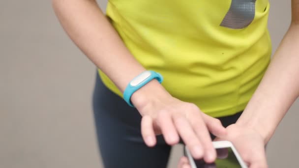 Manos de mujer con una pulsera deportiva y un teléfono inteligente — Vídeos de Stock