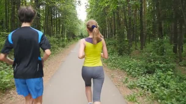 Lyckliga par joggar i parken, slow motion — Stockvideo