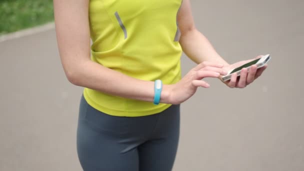 Mãos das mulheres com uma pulseira esportiva e telefone inteligente — Vídeo de Stock